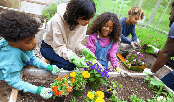 3 kids gardening with her mother in a garden